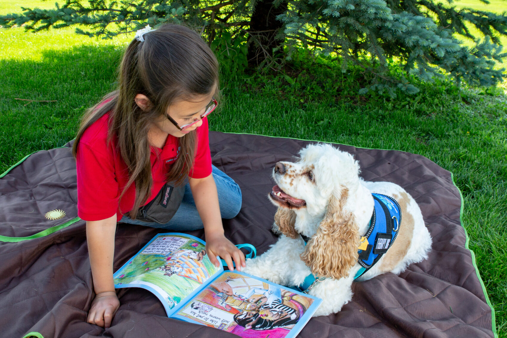 Child reading a book to a therapy dog