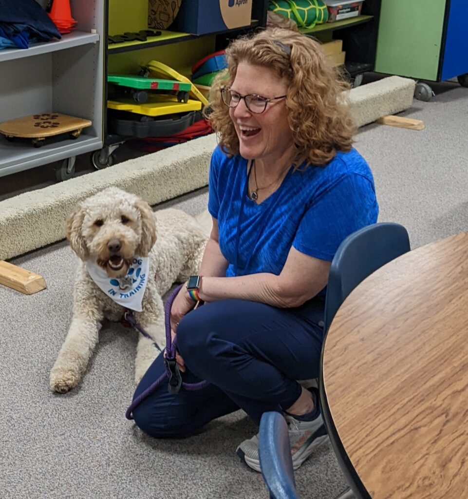 Smiling teacher and dog in a classroom