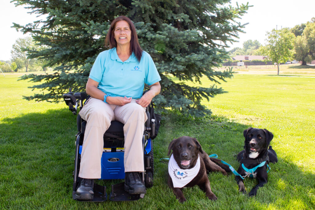 Lisa Hayes in wheelchair with 2 dogs lying next to her