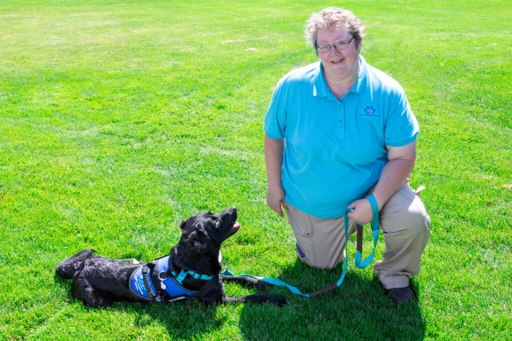 Lisa Walters kneeling on one knee with a medium size dog looking up at her adoringly