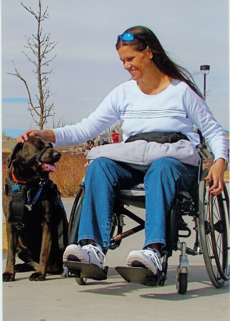 Woman in manual wheelchair petting her service dog 