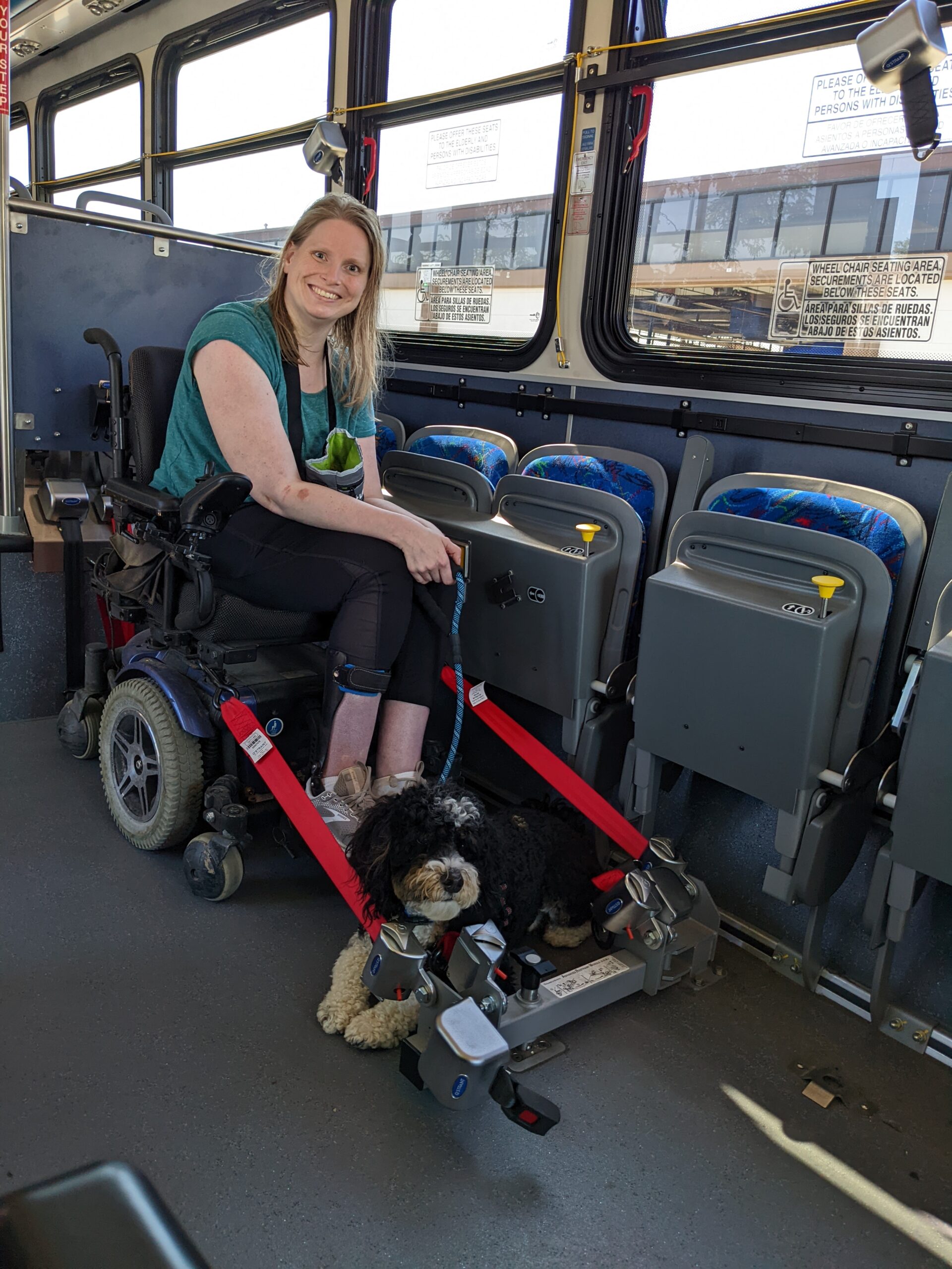 Woman in a power wheelchair on a bus with her service dog